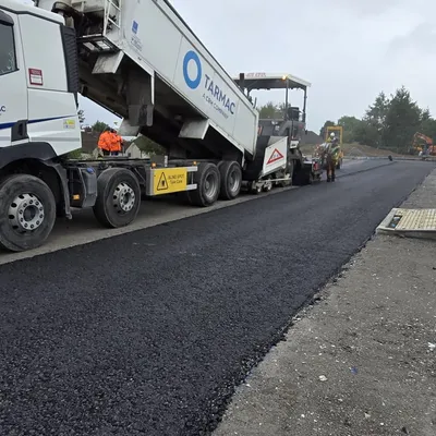 Tarmac delivery lorry feeding asphalt surfacing works