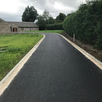 Freshly surfaced rural driveway with kerb edging and grass verge