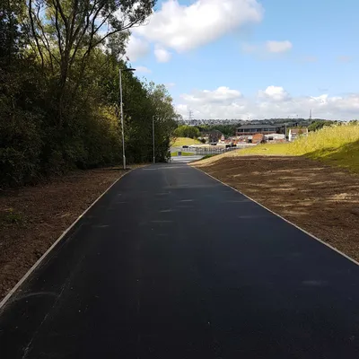 Newly surfaced private access road running downhill through landscaped grounds